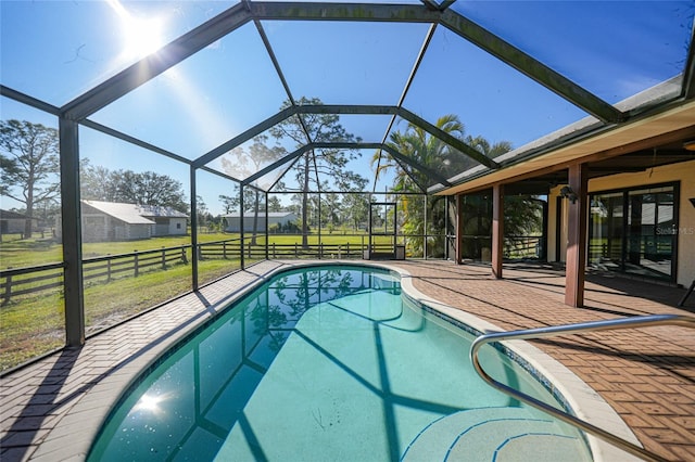 pool with a lanai, a patio area, and a lawn