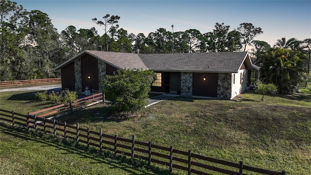 view of front of house with stone siding, a front lawn, and fence