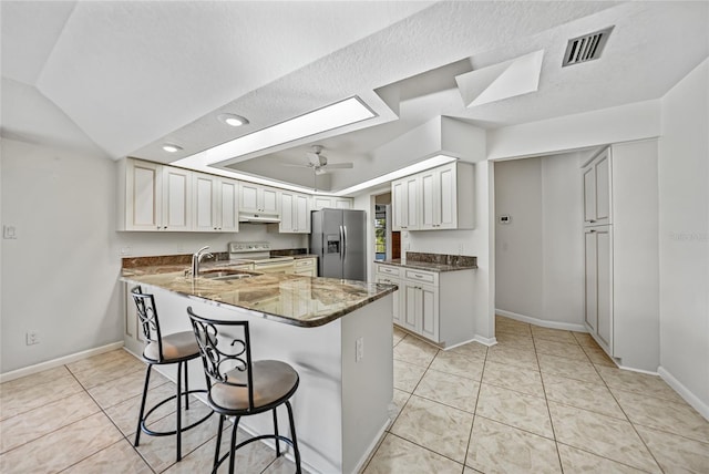 kitchen with stainless steel refrigerator with ice dispenser, white electric range, visible vents, a ceiling fan, and a sink