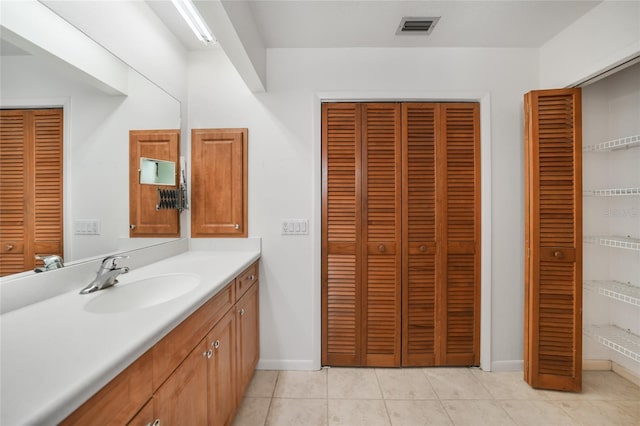 bathroom featuring baseboards, visible vents, tile patterned floors, vanity, and a closet