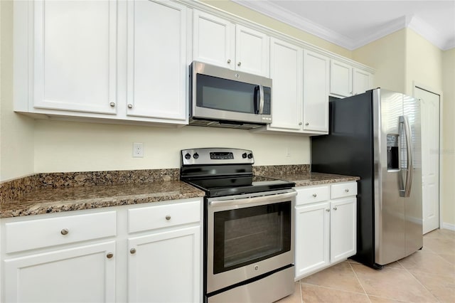 kitchen with ornamental molding, dark stone counters, stainless steel appliances, light tile patterned floors, and white cabinetry