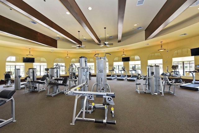 exercise room with ceiling fan and a high ceiling