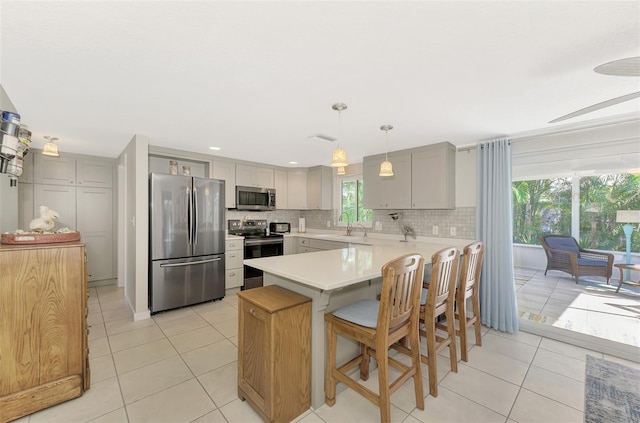 kitchen featuring sink, hanging light fixtures, stainless steel appliances, tasteful backsplash, and light tile patterned floors