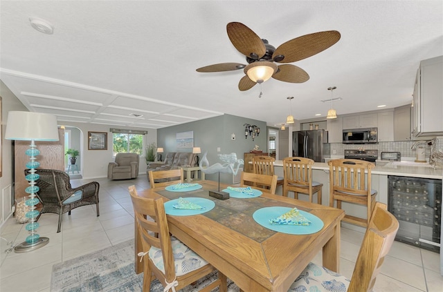 tiled dining space with wine cooler, ceiling fan, and sink