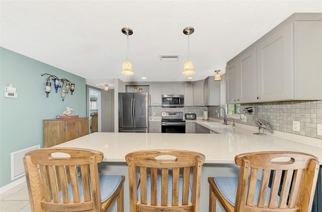 kitchen with sink, a kitchen breakfast bar, kitchen peninsula, gray cabinets, and appliances with stainless steel finishes