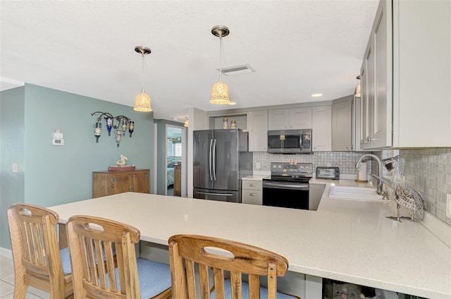 kitchen with kitchen peninsula, a kitchen breakfast bar, stainless steel appliances, sink, and gray cabinets