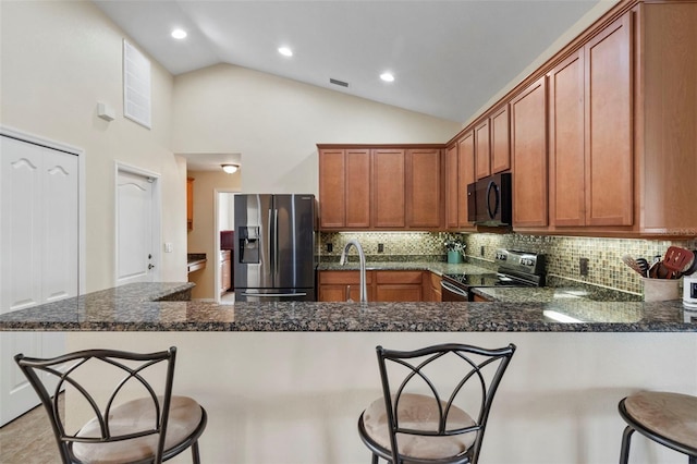 kitchen with kitchen peninsula, black appliances, tasteful backsplash, and a breakfast bar