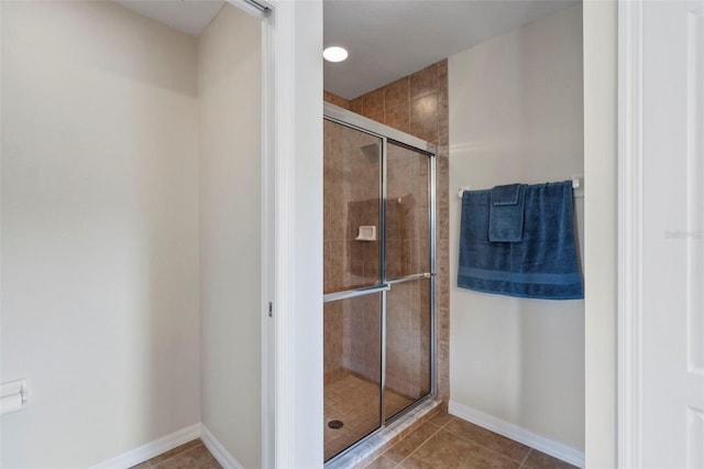 bathroom with a shower with door and tile patterned floors