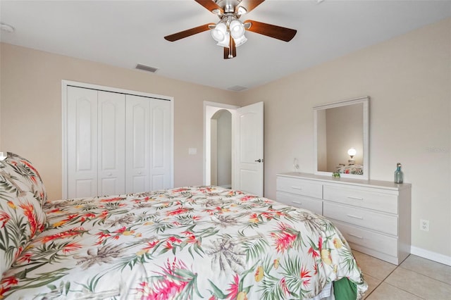 tiled bedroom with ceiling fan and a closet