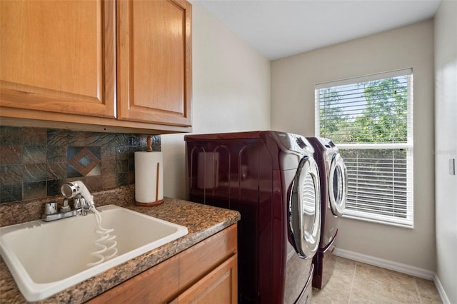 clothes washing area featuring sink, cabinets, and washer and clothes dryer