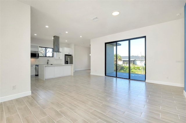 unfurnished living room featuring a wealth of natural light and sink