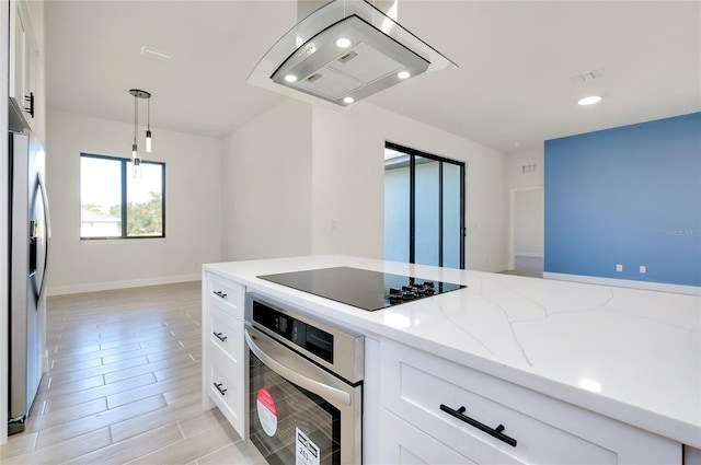 kitchen featuring light stone countertops, appliances with stainless steel finishes, decorative light fixtures, white cabinetry, and island exhaust hood