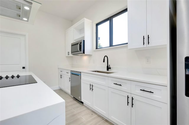 kitchen featuring white cabinets, appliances with stainless steel finishes, light stone counters, and sink