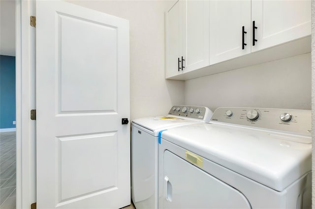 clothes washing area with washer and dryer and cabinets