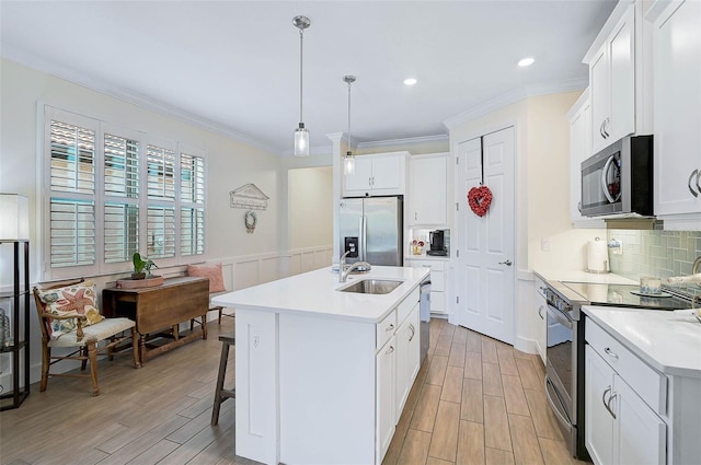 kitchen featuring a kitchen island with sink, white cabinets, pendant lighting, stainless steel appliances, and a breakfast bar area