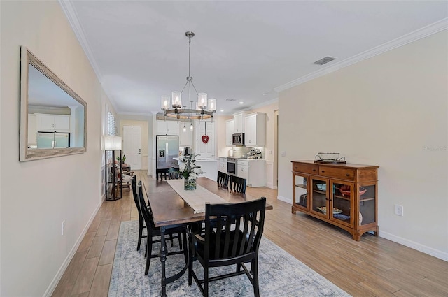 dining room with an inviting chandelier, crown molding, and light wood-type flooring