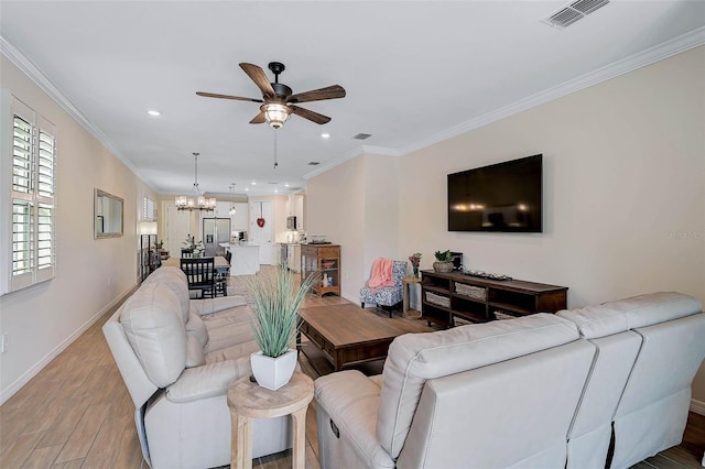 living room with ceiling fan with notable chandelier, light hardwood / wood-style flooring, and ornamental molding