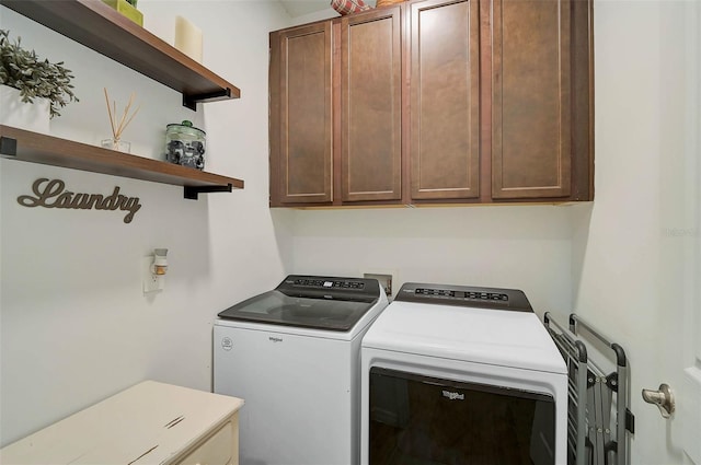 clothes washing area featuring cabinets and washer and clothes dryer