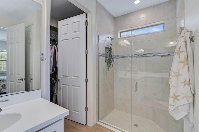 bathroom featuring wood-type flooring, walk in shower, and vanity