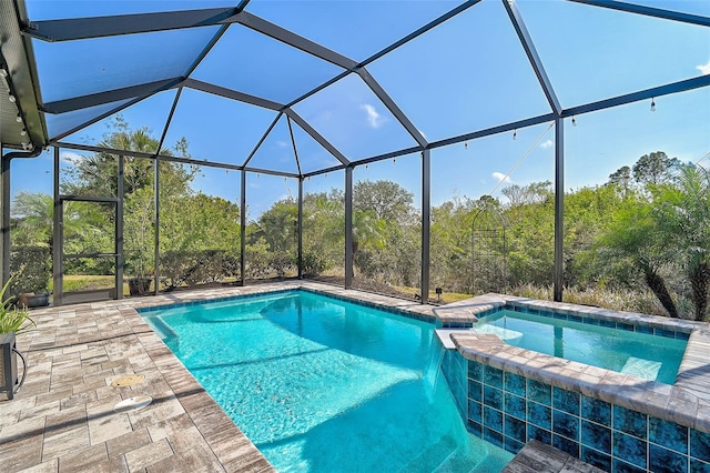 view of pool with glass enclosure, an in ground hot tub, and a patio