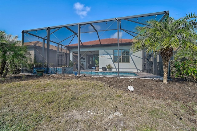 rear view of house with glass enclosure, a patio area, and a yard