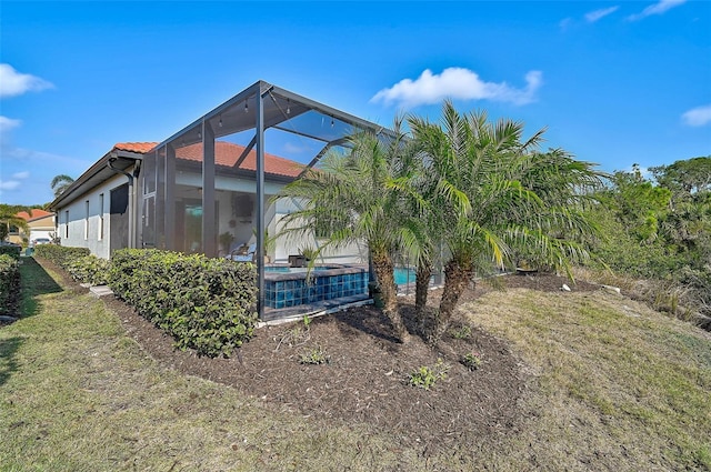 view of side of home featuring a lanai and a yard