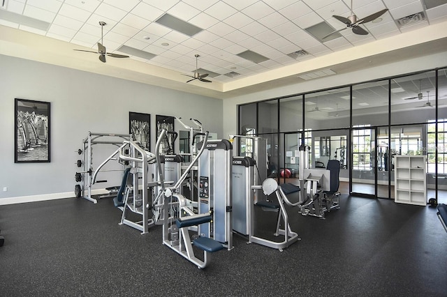 exercise room with ceiling fan, a paneled ceiling, and a towering ceiling