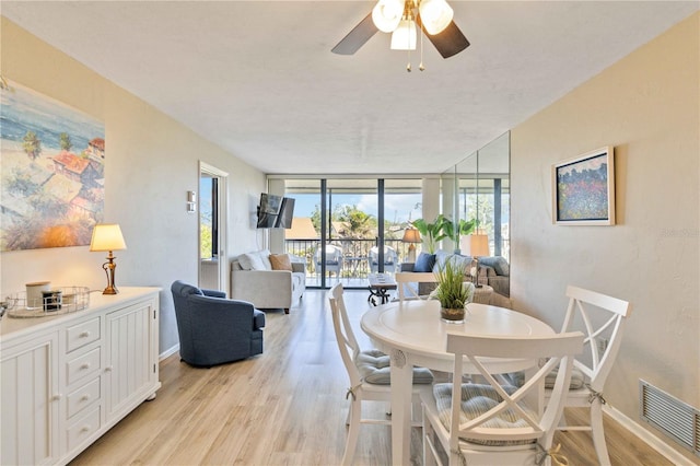 dining room with ceiling fan, expansive windows, and light hardwood / wood-style flooring