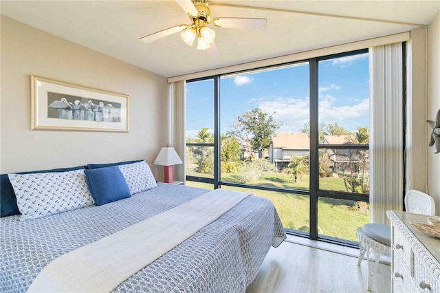 bedroom with light hardwood / wood-style flooring, expansive windows, and ceiling fan