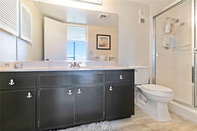 bathroom with tile patterned floors, vanity, toilet, and a shower with door