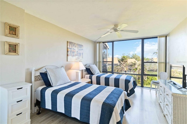 bedroom with ceiling fan, light hardwood / wood-style floors, and a wall of windows