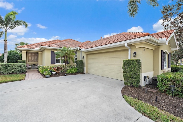 mediterranean / spanish house with stucco siding, concrete driveway, an attached garage, and a tiled roof