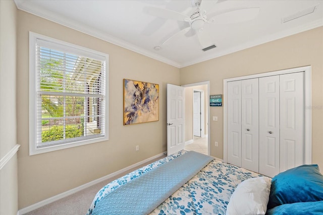 bedroom with ornamental molding, a closet, ceiling fan, and light colored carpet