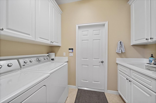 clothes washing area featuring washer and dryer, cabinets, light tile patterned floors, and sink