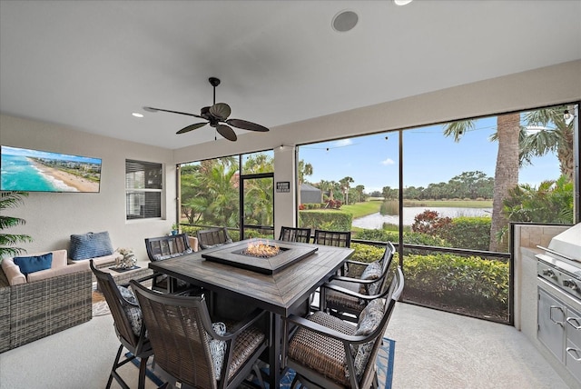 sunroom / solarium featuring ceiling fan and a water view