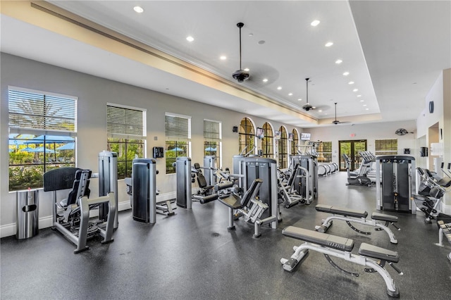 workout area with a tray ceiling, a wealth of natural light, and ceiling fan