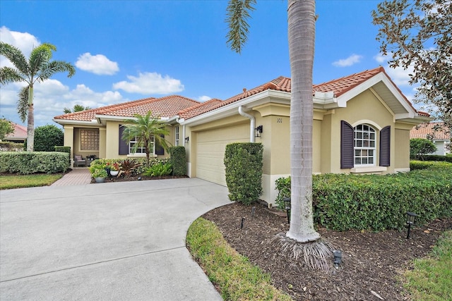 mediterranean / spanish house with a tiled roof, an attached garage, driveway, and stucco siding