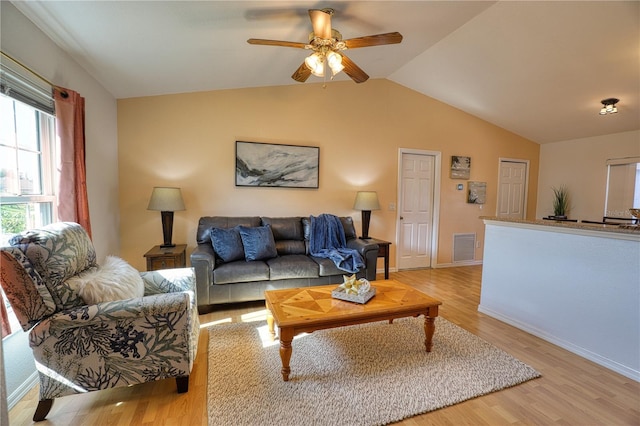 living room featuring lofted ceiling, ceiling fan, light wood-type flooring, and a wealth of natural light