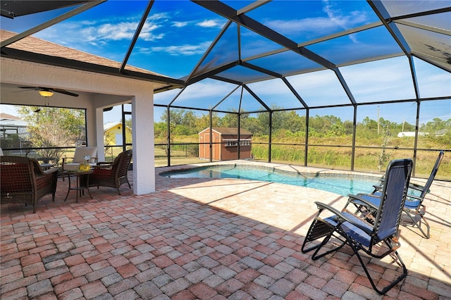 view of swimming pool featuring ceiling fan, a storage unit, a patio area, and glass enclosure