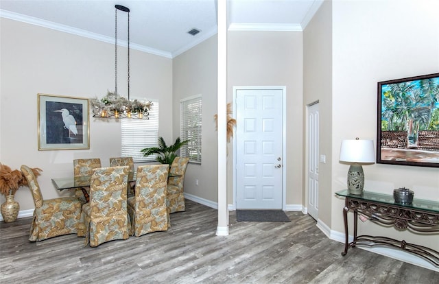 dining space with crown molding, wood-type flooring, and a high ceiling