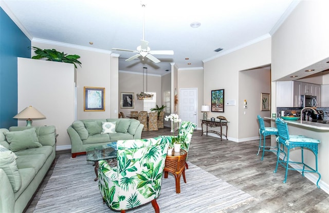 living room featuring ceiling fan, light wood-type flooring, and ornamental molding