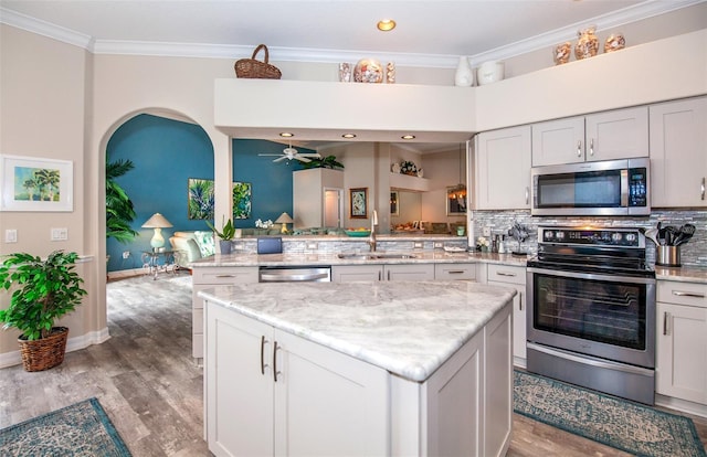 kitchen with sink, ornamental molding, tasteful backsplash, kitchen peninsula, and stainless steel appliances