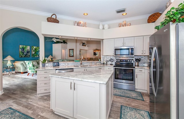 kitchen featuring sink, backsplash, kitchen peninsula, crown molding, and appliances with stainless steel finishes