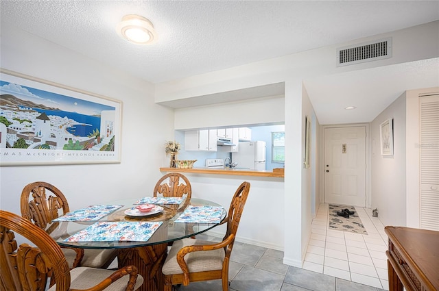 tiled dining area featuring a textured ceiling