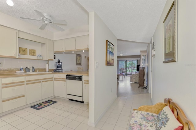 kitchen featuring white dishwasher, sink, ceiling fan, light tile patterned floors, and a textured ceiling