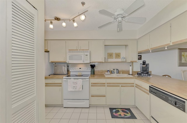 kitchen featuring white appliances, a textured ceiling, and cream cabinets