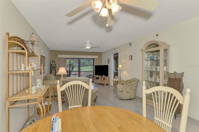 dining room featuring a textured ceiling, light wood-type flooring, and ceiling fan