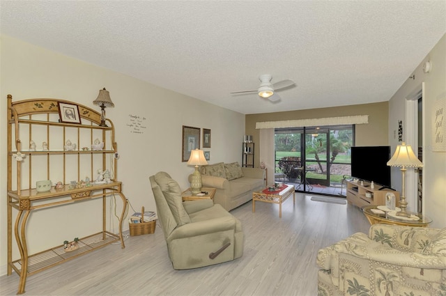 living room with ceiling fan, a textured ceiling, and light hardwood / wood-style flooring