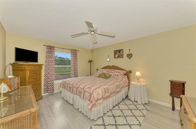 bedroom with a textured ceiling, light hardwood / wood-style flooring, and ceiling fan