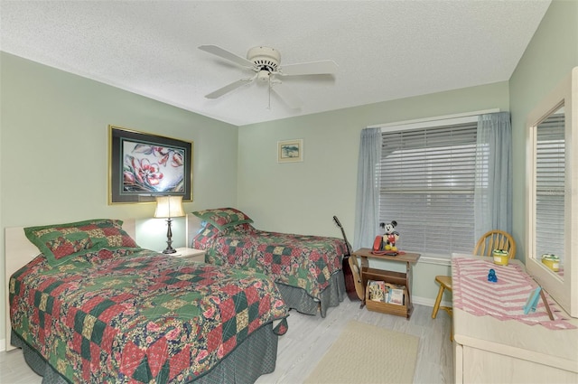 bedroom with ceiling fan, light hardwood / wood-style floors, and a textured ceiling